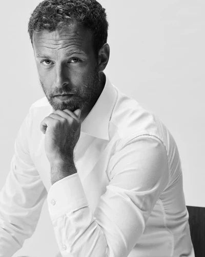 A black and white portrait of a man in a white custom made shirt