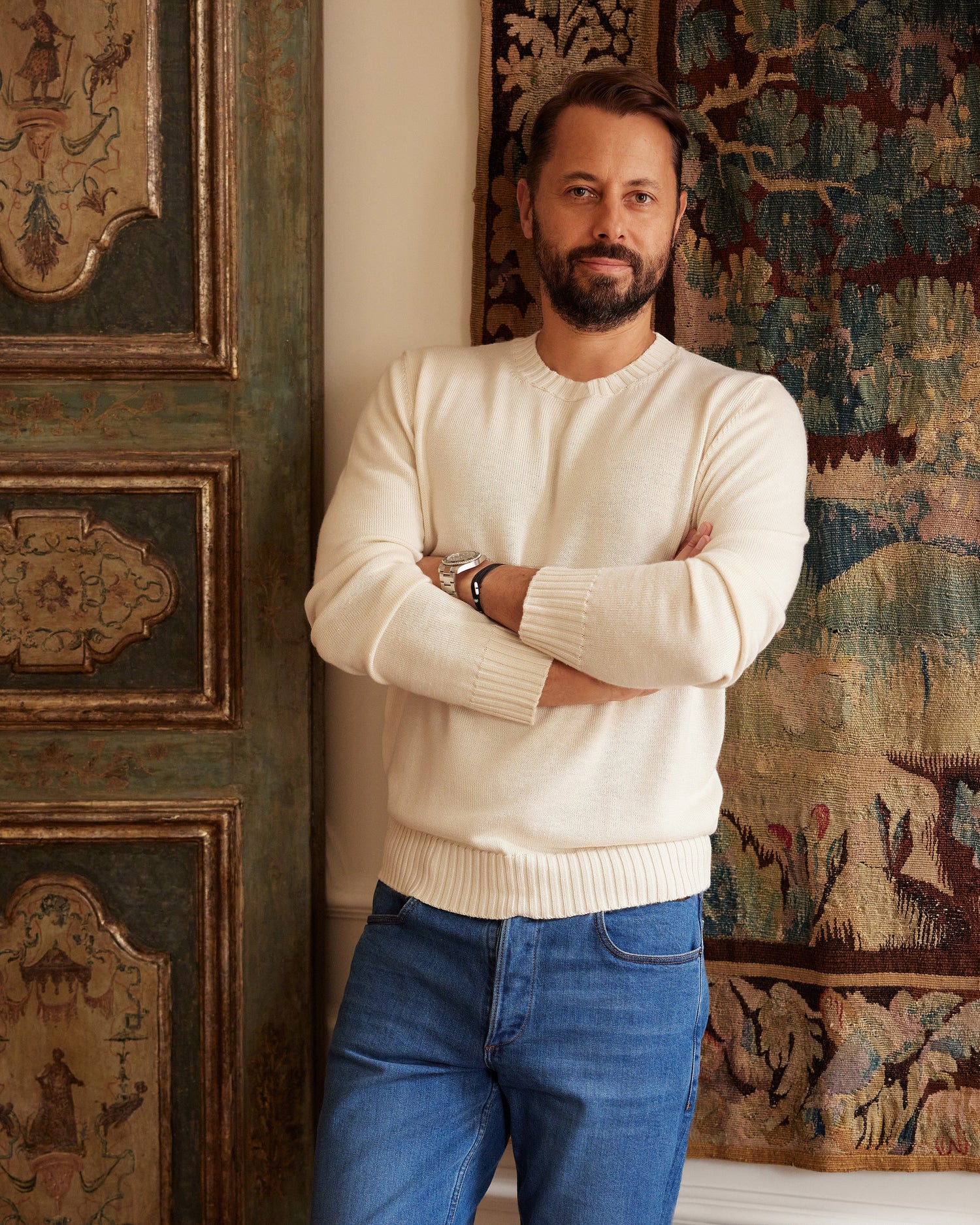 A man with crossed arms over his chest leaning onto a wall